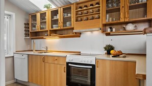 Une cuisine avec des meubles en bois, un plan de travail blanc, une cuisinière et un lave-vaisselle.