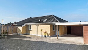 Une maison d’habitation avec un toit en tuiles, une véranda et un garage.