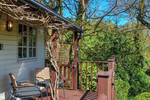A wooden deck with a railing, a chair, and a table.