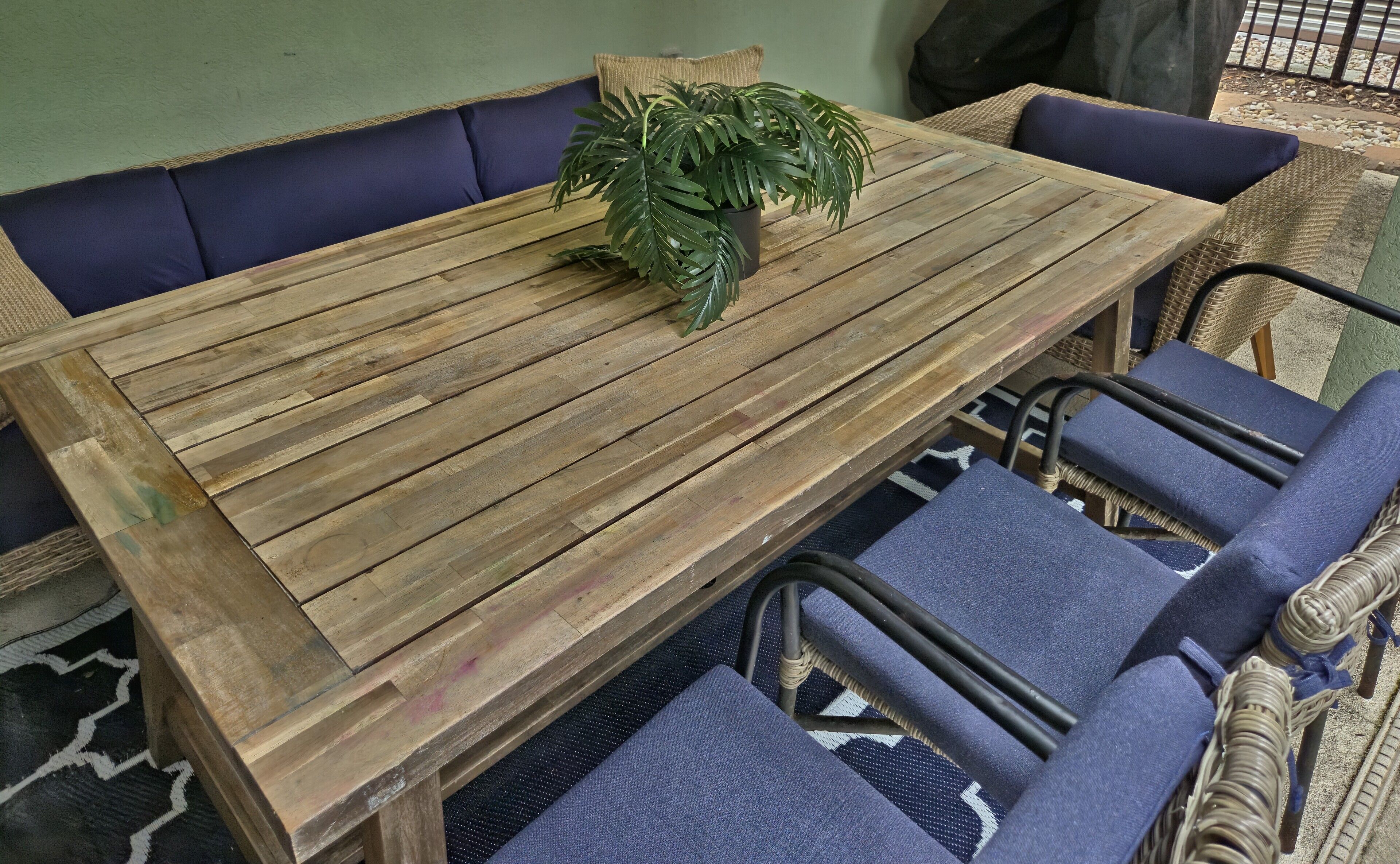 Una mesa de madera con una planta en maceta, rodeada de sillas tapizadas en azul.