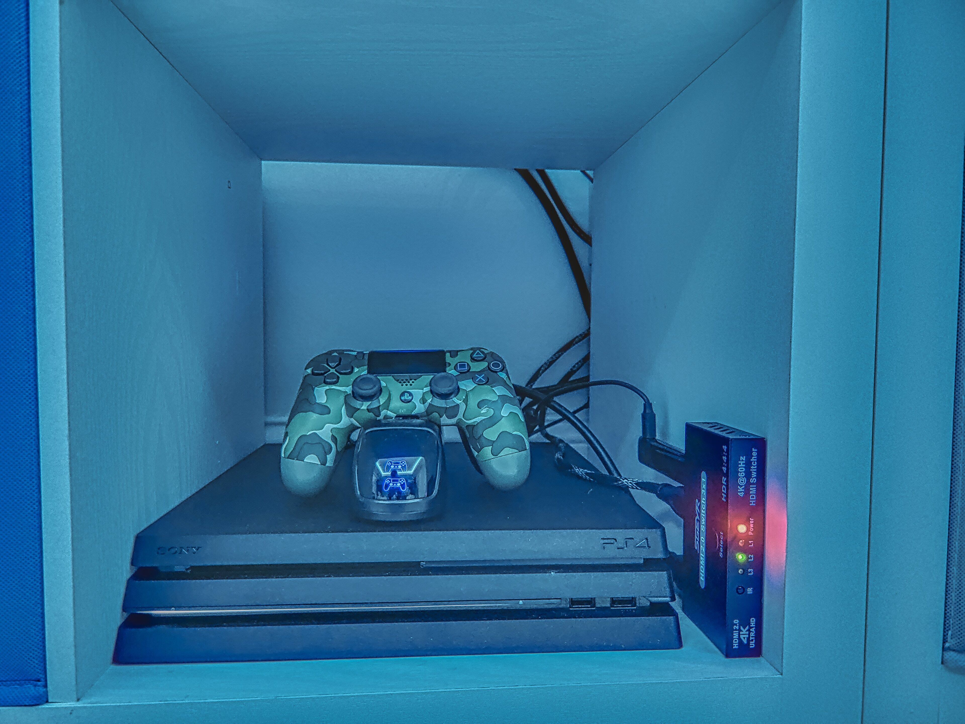A gaming console with a controller and a headset, placed on a shelf.