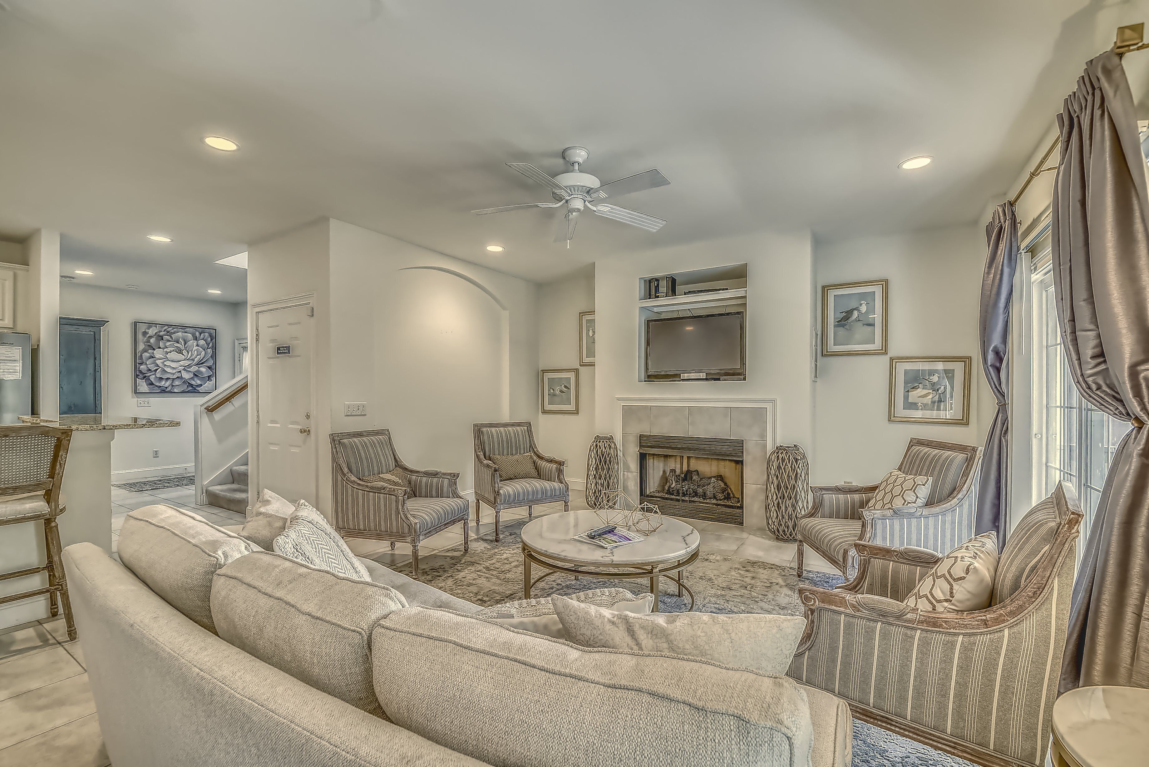 A living room with a sofa, chairs, a coffee table, a fireplace, and a ceiling fan.