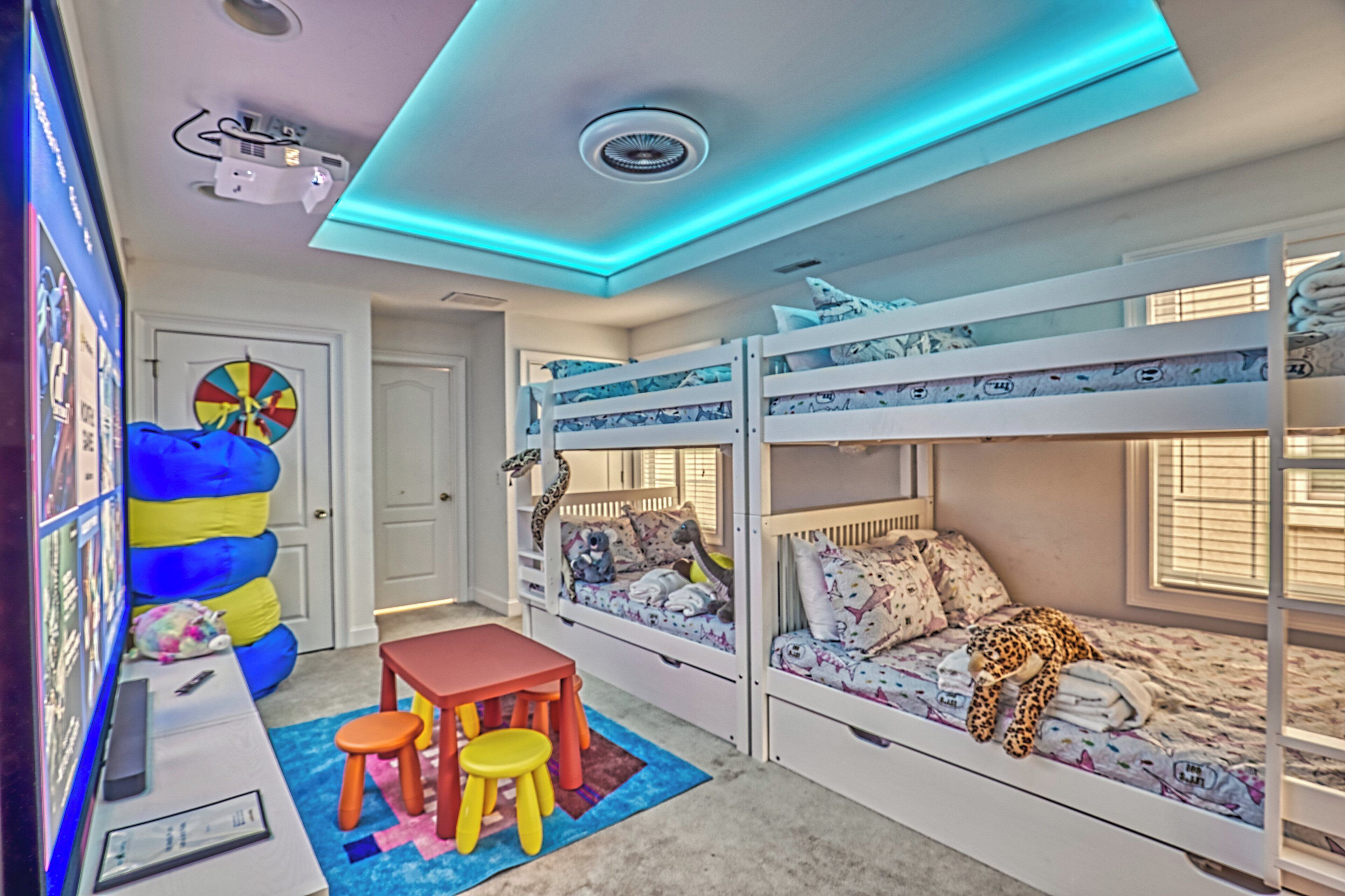 Ein Kinderzimmer mit Etagenbetten, einem Schreibtisch und einer bunten Spielgegend.