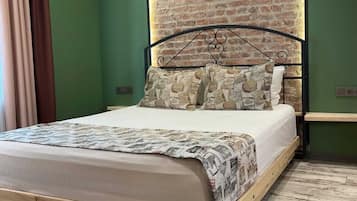 A bedroom with a brick wall, a wooden bed frame, and a green wall.