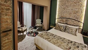 A bedroom with a brick wall, a bed with patterned bedding, a chair, and a small table with a tray. - Anka Residence (Ankara)