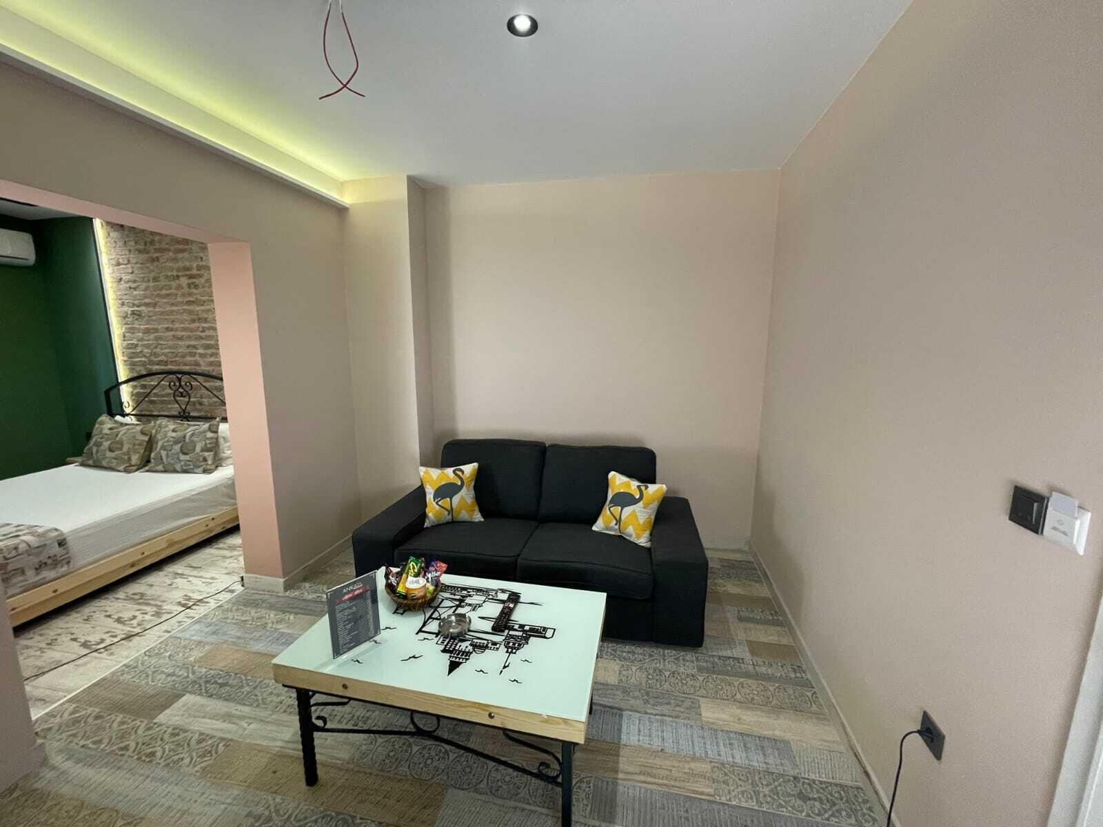 A compact living space with a bed, a sofa, and a small table with a laptop.