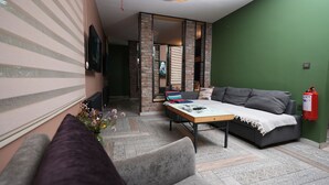 A cozy living room with a grey sofa, a wooden coffee table, and a green wall. - Anka Residence (Ankara)