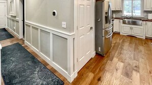 A modern kitchen with white cabinetry, a stainless steel refrigerator, and a wooden floor.