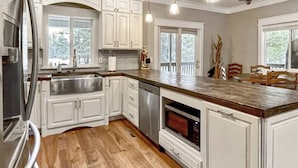 A kitchen with white cabinets, a stainless steel refrigerator, a wooden countertop, and a built-in oven.