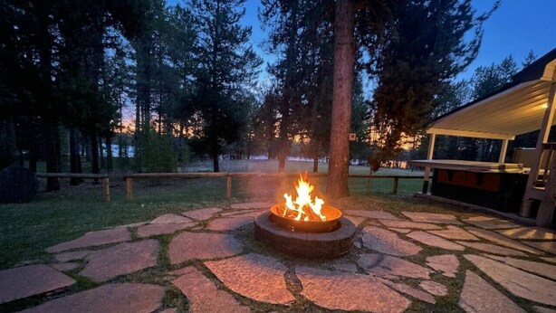 A stone fire pit surrounded by a stone pathway, with a building in the background.