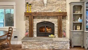 A stone fireplace with a wooden mantel, a cow skull decoration, and an American flag.