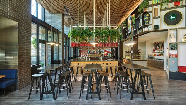 A modern cafe with high ceilings, wooden beams, and a central bar area. - citizenM Seattle Pioneer Square (Seattle)