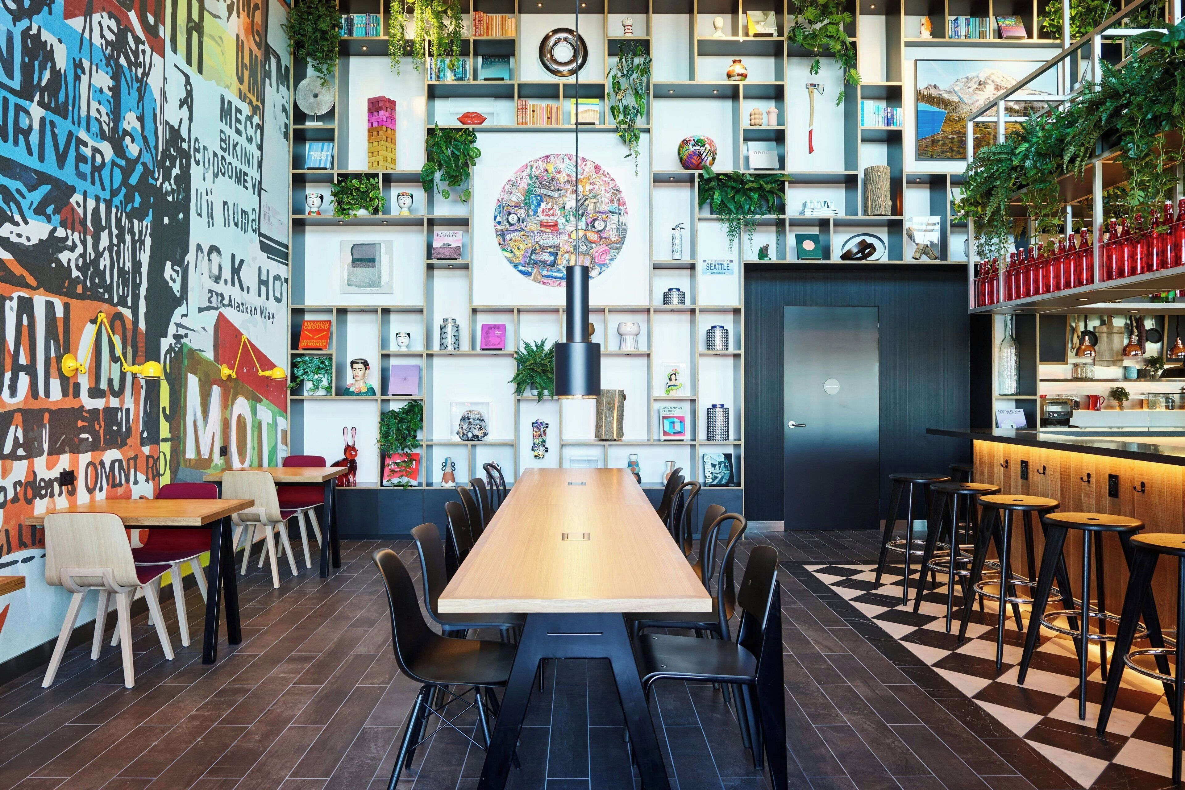 A modern restaurant with a long wooden table, black chairs, and a checkered floor.