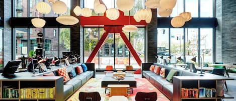 A modern library with bookshelves, seating areas, and large windows offering views of the city.