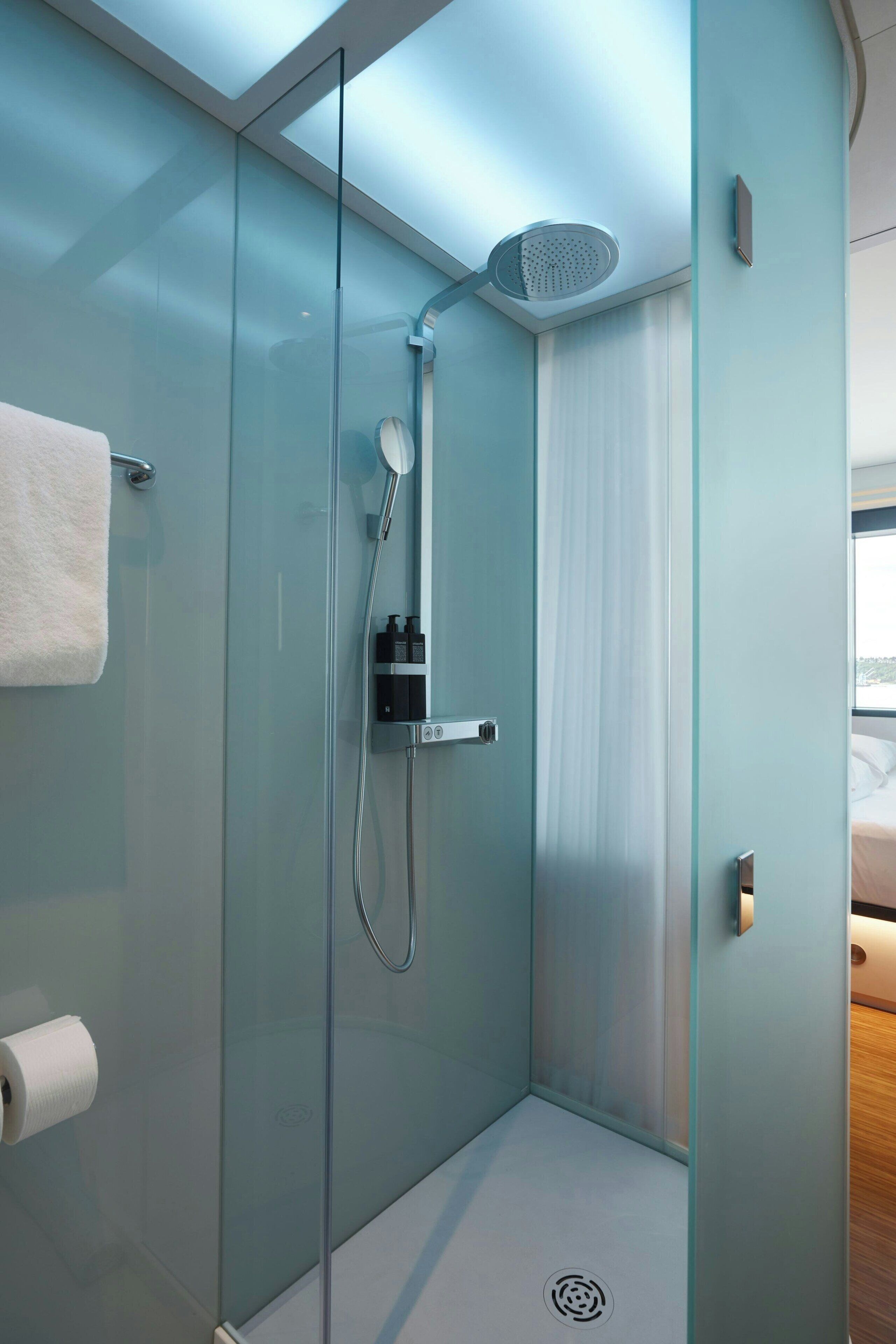 A modern shower with a glass enclosure, a handheld showerhead, and a towel rack.