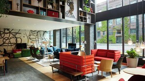 A modern interior with a high ceiling, open space, and large windows offering a view of the street. - citizenM Seattle Pioneer Square (Seattle)