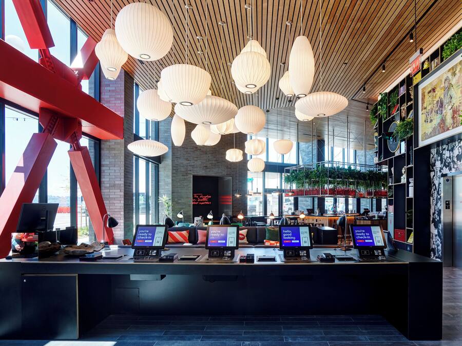 A modern check-in area with multiple computer stations, wooden ceiling, and large windows.