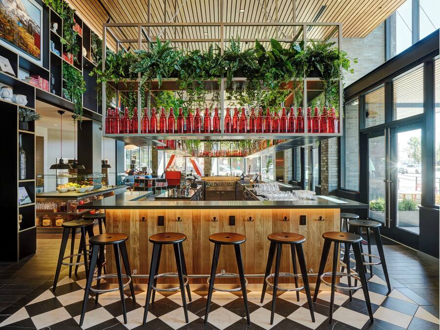 A modern bar area with a checkered floor, wooden bar counter, and stools.