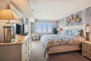A bedroom with a bed, dresser, lamp, and wall decor.