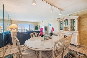 A dining area with a round table, chairs, a cabinet, and a sofa.