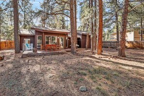 Une cabane dotée d’une terrasse, entourée de grands pins.