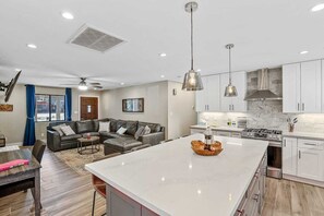 Une cuisine moderne avec des meubles blancs, un îlot central et des luminaires suspendus.