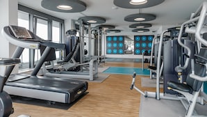 Et fitnesscenter med løbebånd, styrkemaskiner og en væg med nummererede træningsstationer.