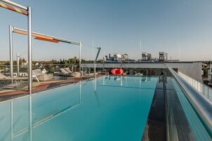 Una piscina en la azotea con vistas claras de los edificios circundantes y un flotador rojo inflable.