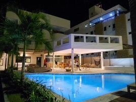 Un hotel moderno con piscina, area salotto all'aperto e portico.