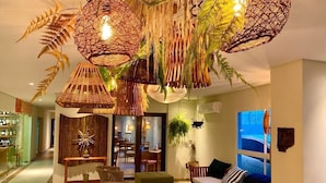 A room with wicker hanging lamps, a green sofa, and a dining area.