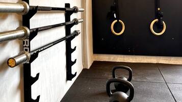 Un gimnasio con pesas rusas, una estructura para sentadillas y bandas de resistencia.