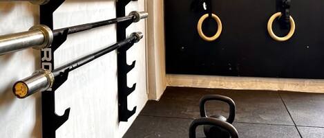 A gym with kettlebells, a squat rack, and resistance bands.