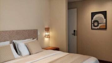 Habitación de hotel con una cama grande, una mesita de noche, una lámpara de pared y un cuadro en la pared.