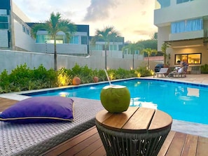 Relax by the serene pool surrounded by lush greenery and palm trees.