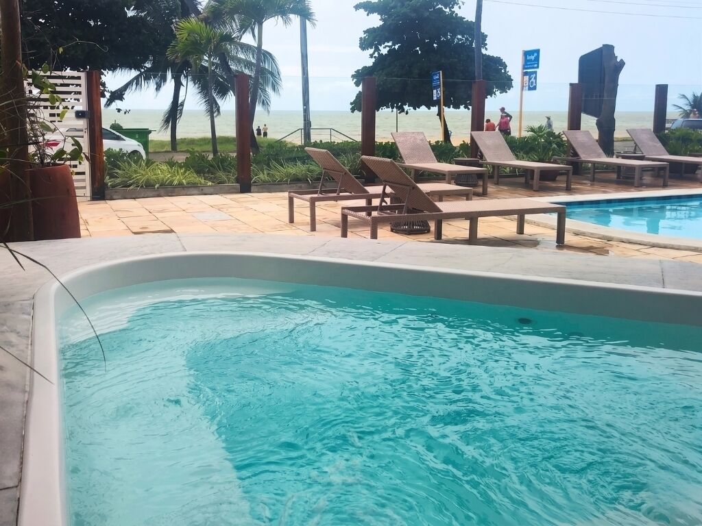 Une piscine avec des chaises longues, une vue sur la plage et un panneau indiquant un classement de trois étoiles.