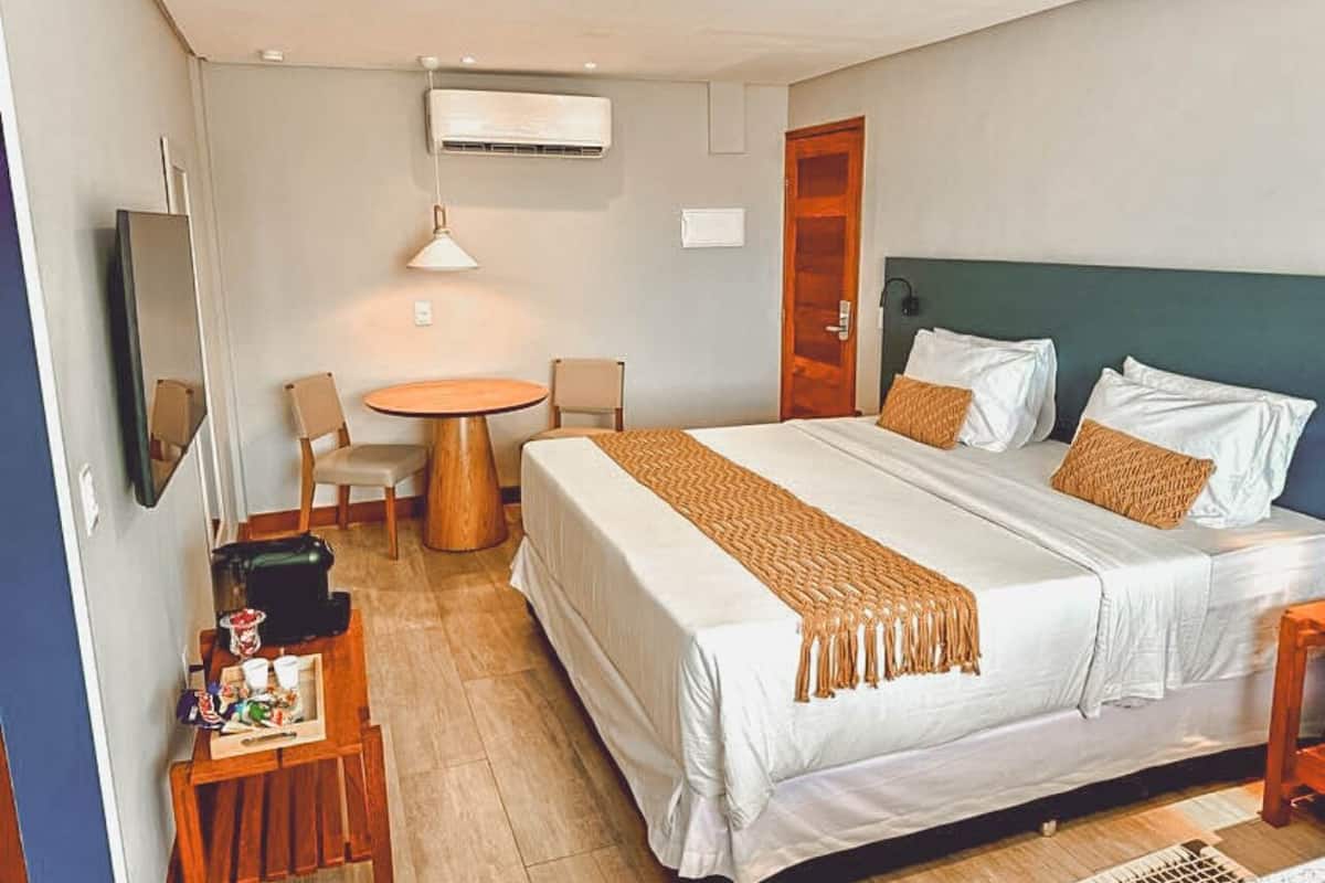 Habitación de hotel con cama, escritorio, silla, mesa redonda y televisor.