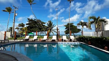 Una piscina al aire libre, sillones reclinables de piscina