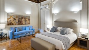 Ein Schlafzimmer mit einem großen Bett, einem blauen Sofa, einem Couchtisch und einem Bild an der Wand.