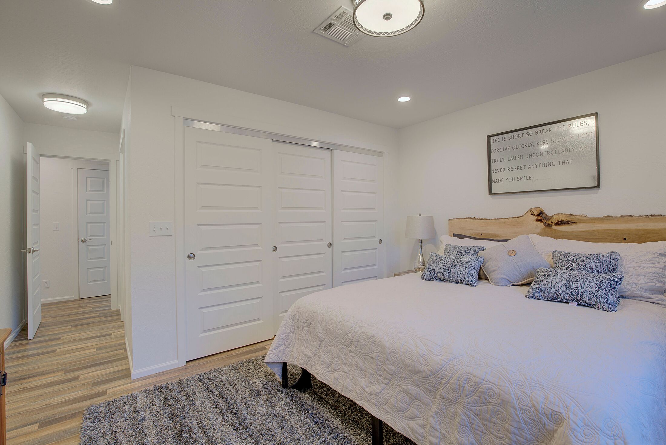 A bedroom with a large bed, white walls, and a ceiling light.
