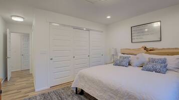 A bedroom with a large bed, white walls, and a ceiling light.