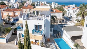 A residential area with a swimming pool, multiple buildings, and a view of the sea.