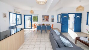A spacious living area with a dining table, blue doors, and a large window.