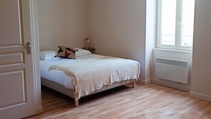 Quarto com cama, mesa de cabeceira, abajur e janela.