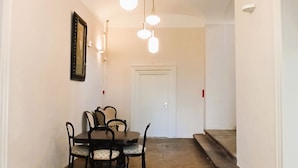 Uma área de refeições com uma mesa e cadeiras, um lustre pendurado e uma escada que leva a outro cômodo.