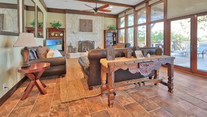 A spacious living room with a fireplace, leather sofas, and a large window offering a view of the outdoors.