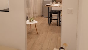 Een moderne keuken met witte kasten, een koelkast en een eethoek met een tafel en stoelen.