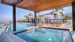 A pool area with a view of the city skyline, including a tall tower. - Penthouse 1BR + Rooftop Paradise | Romantic Zone (Puerto Vallarta)
