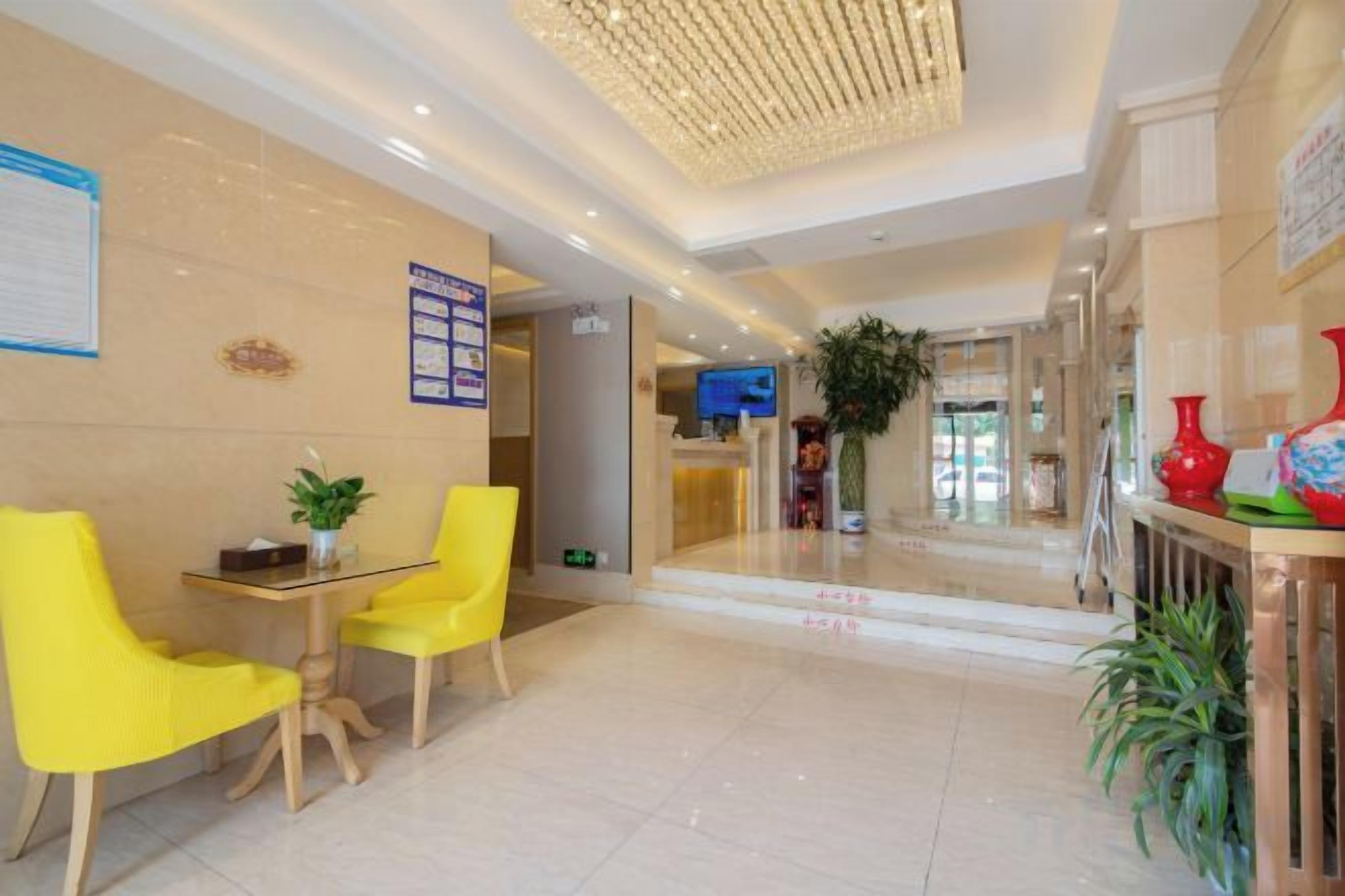 Un vestíbulo de hotel con mostrador de recepción, zona de estar y una planta grande.