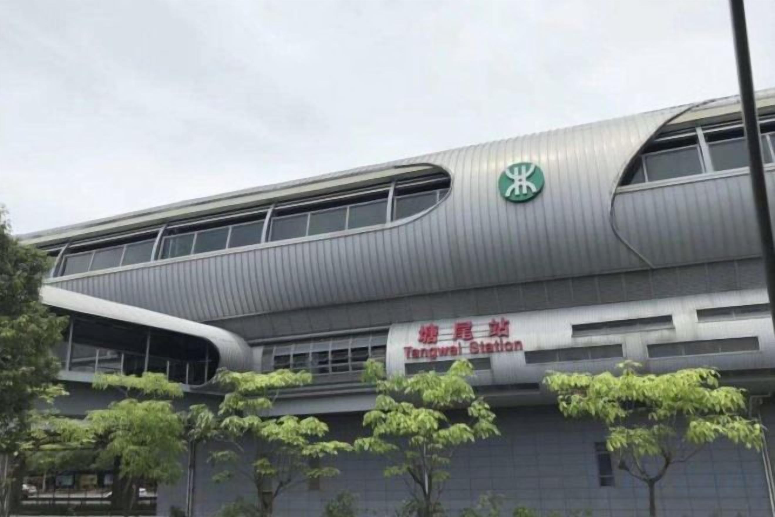 A modern building with a curved roofline and a prominent green logo on the facade.