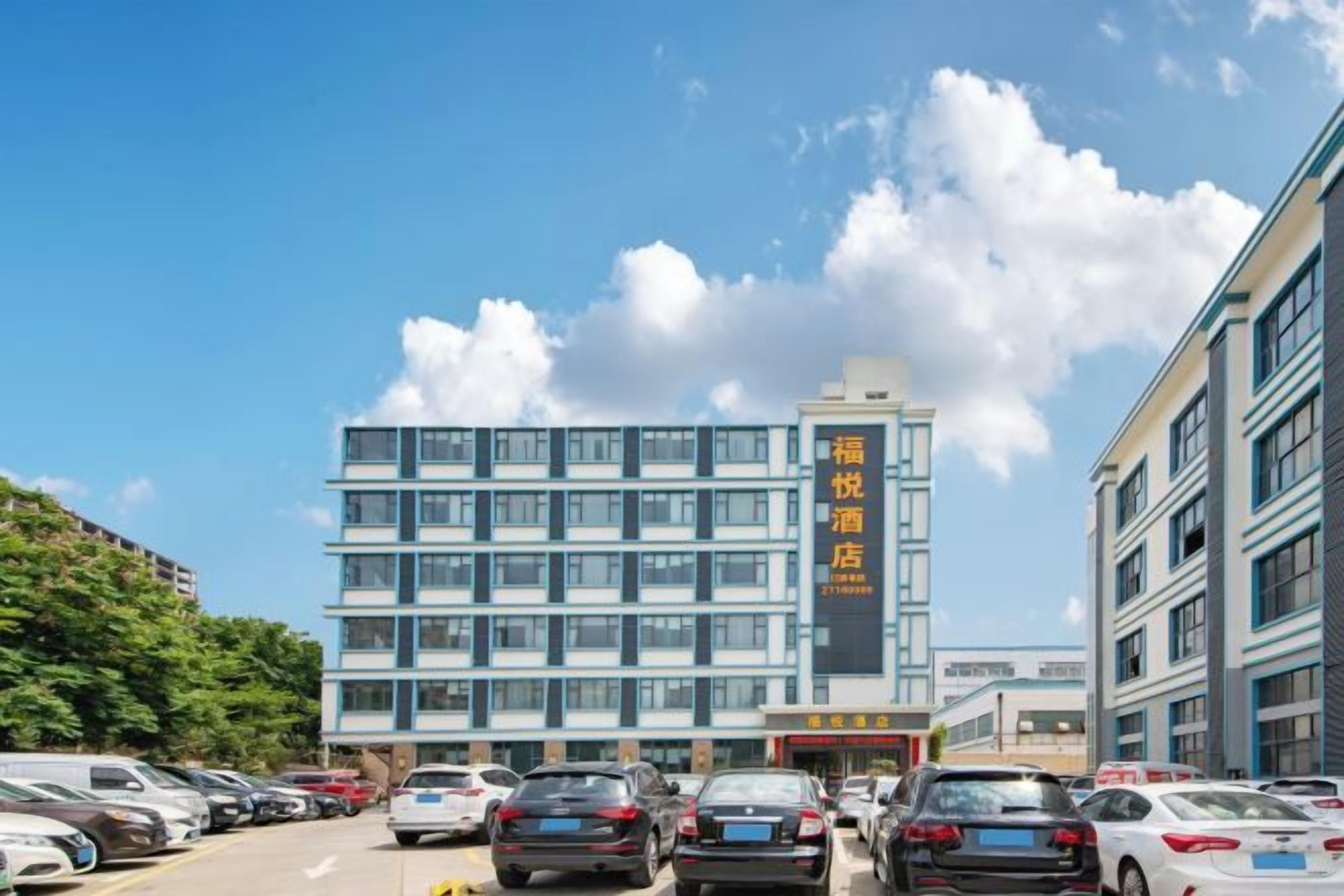 Un hotel de varios pisos con una hilera de ventanas en la planta baja, un estacionamiento al frente y un cielo despejado.